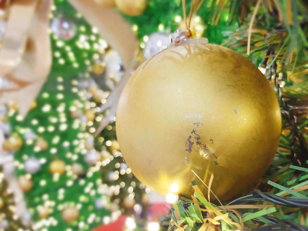 Weihnachtsball, der an Tannenzweigen mit einem festlichen Hintergrund hängt foto