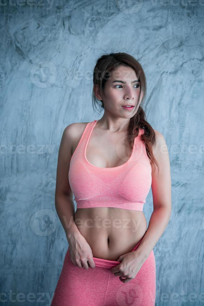 nahaufnahme asiatisches schönes sportmädchen an der wand des fitnessstudios, thailand liebe gesundheit, schlanke frau trainingskonzept foto