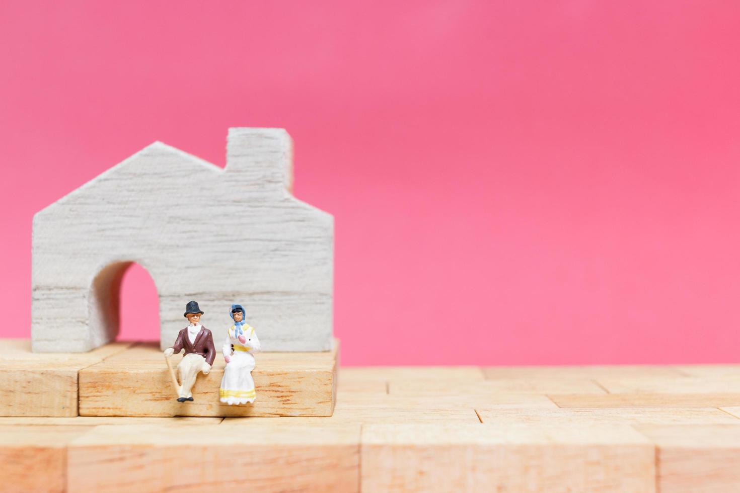 Miniaturpaar mit Häusern auf einem rosa Hintergrund, Valentinstagskonzept foto