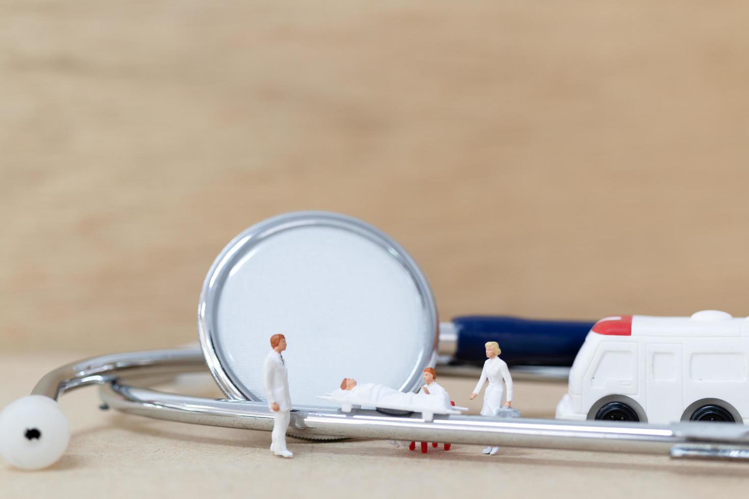 Miniaturärzte mit Krankenschwestern, die einen Patienten auf einer Trage tragen, Gesundheitskonzept foto