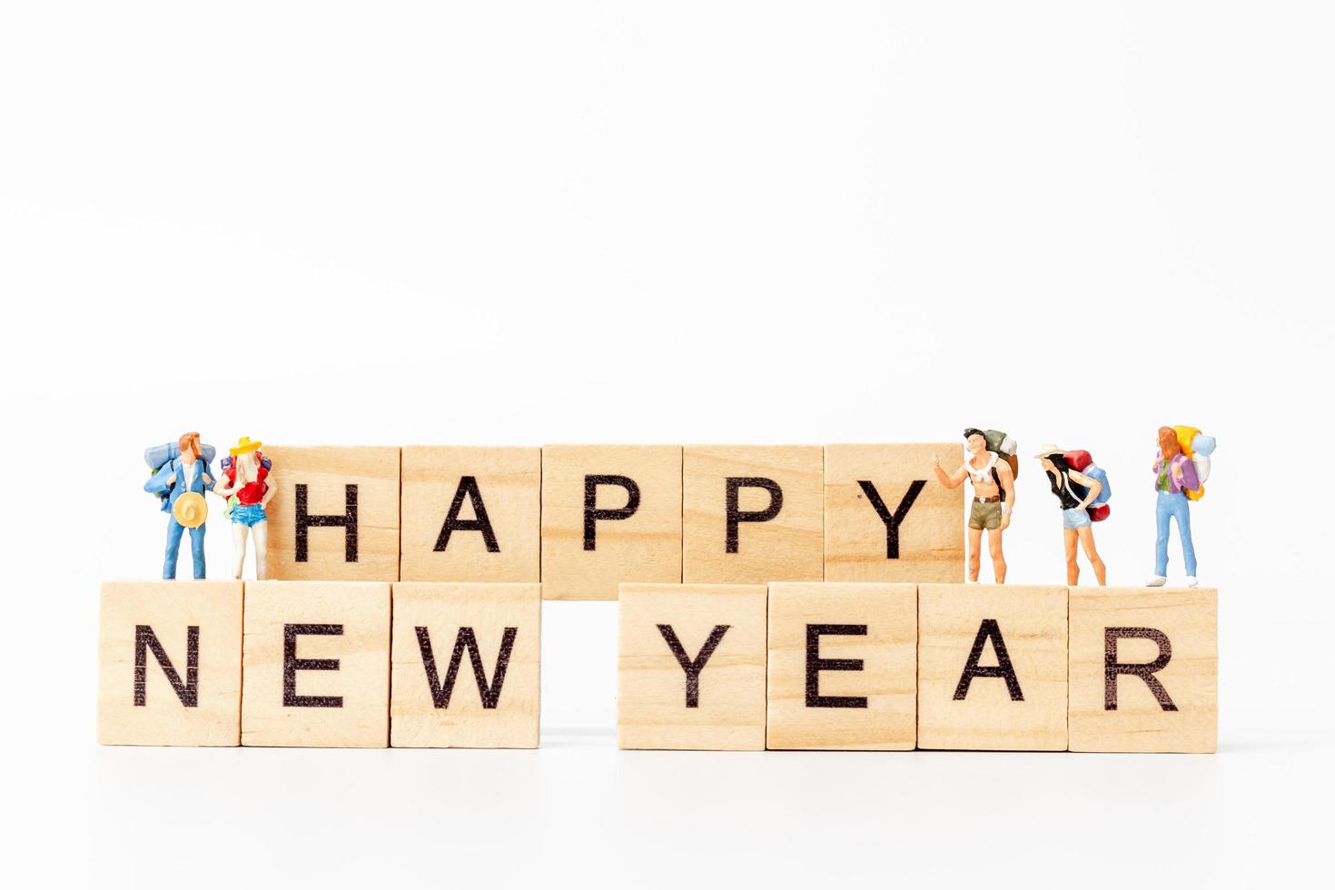 Miniaturmenschen auf Holzklötzen mit dem Text frohes neues Jahr auf einem weißen Hintergrund foto