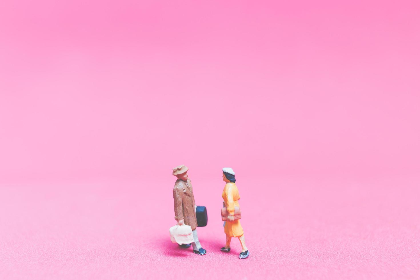 Miniaturpaar von Reisenden auf einem rosa Hintergrund foto