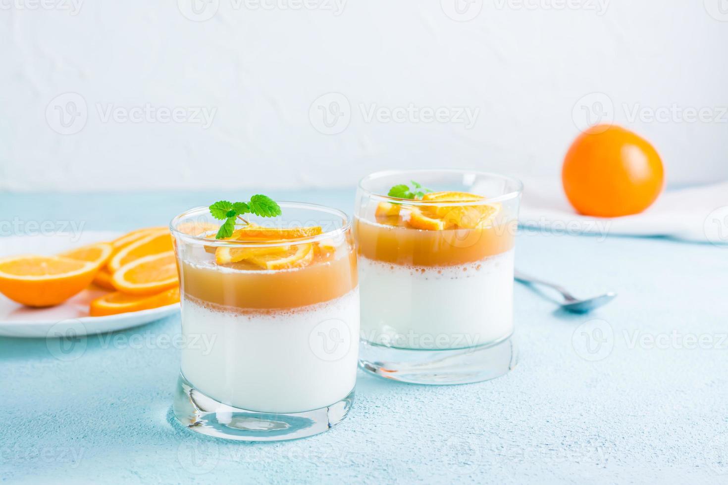 Panna Cotta mit Orange und Minze Blatt im Brille auf ein Licht Tisch. Süss Italienisch Dessert foto