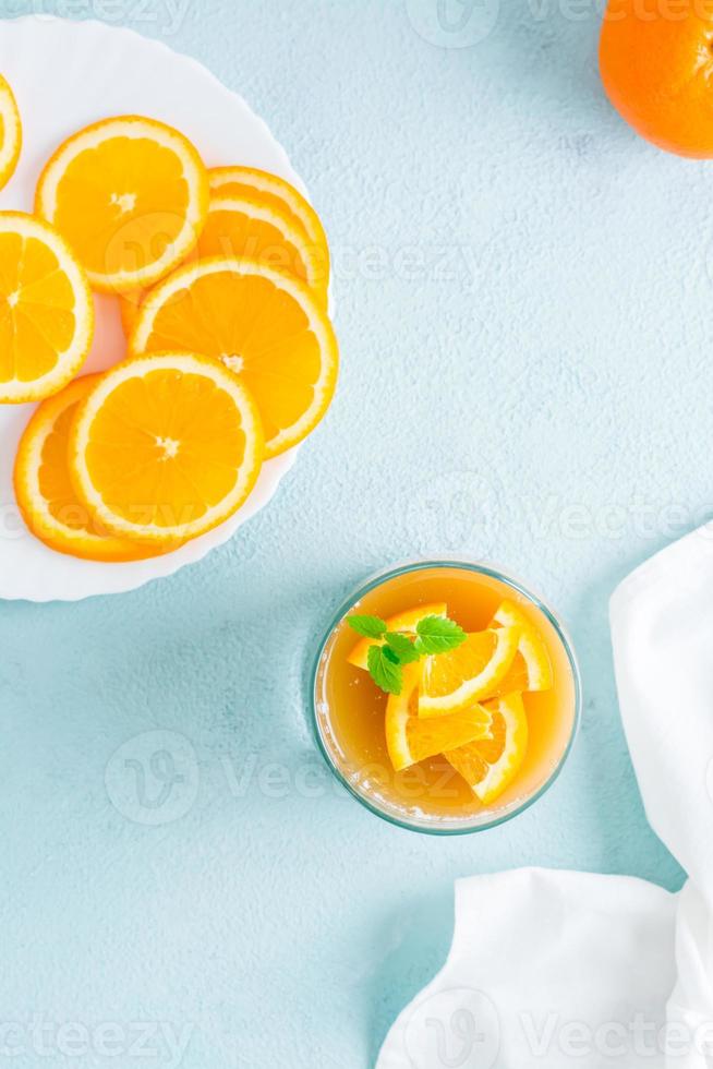 Orange Panna Cotta mit Minze Blatt im Brille und Orange Scheiben auf ein Teller auf ein Licht Tisch. Süss Italienisch Nachtisch. oben und Vertikale Aussicht foto