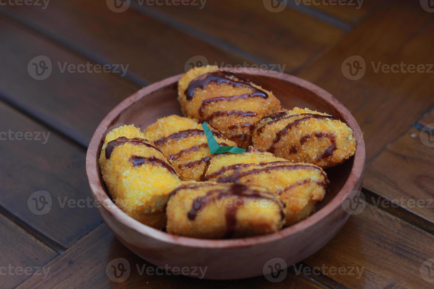 ein schließen oben von Banane Nuggets mit Schokolade Soße Belag serviert auf ein hölzern Schüssel. Essen Konzept Foto. foto