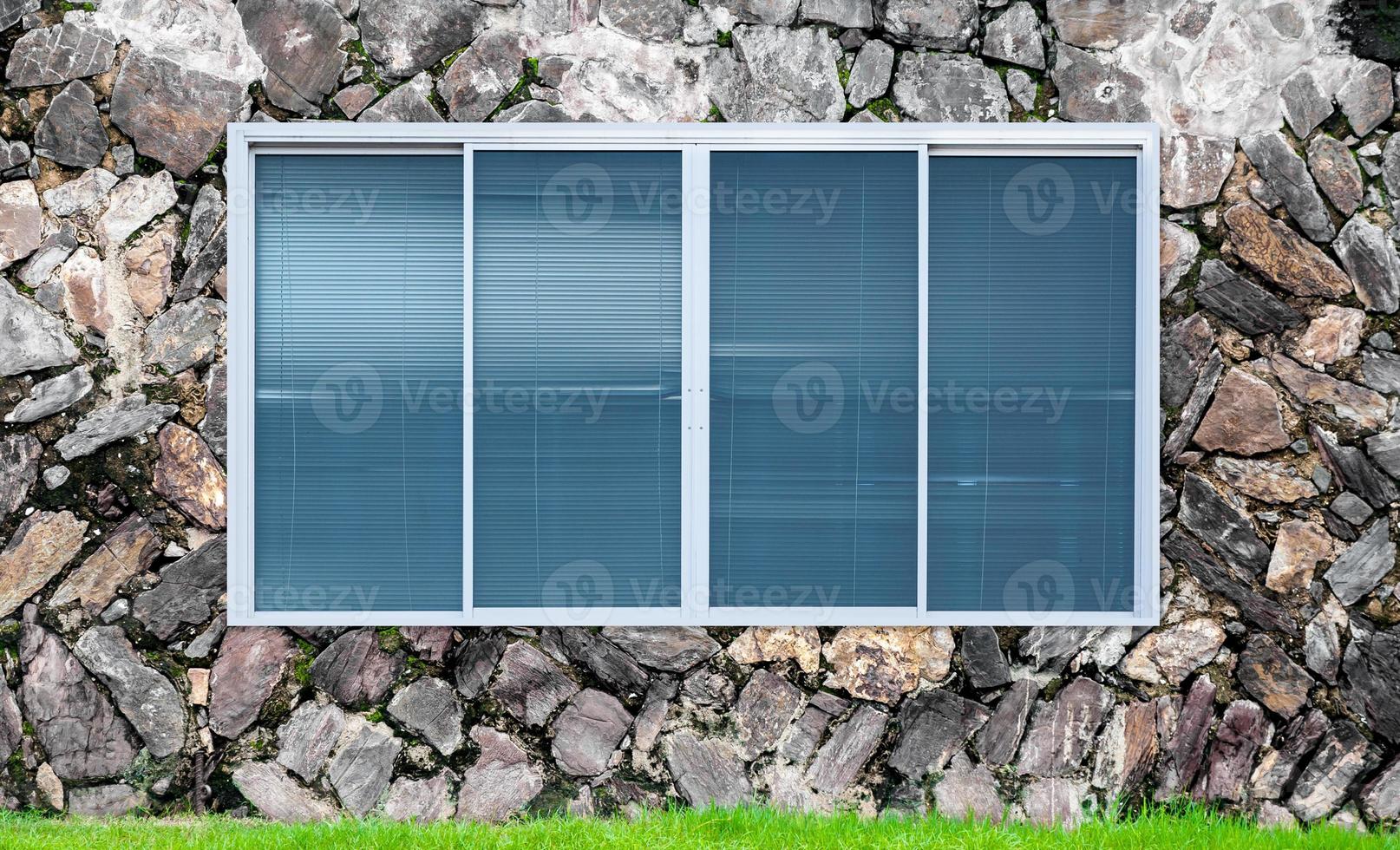 modern Glas Fenster auf das Stein Mauer und Grün Gras, Decke Fenster Rahmen foto