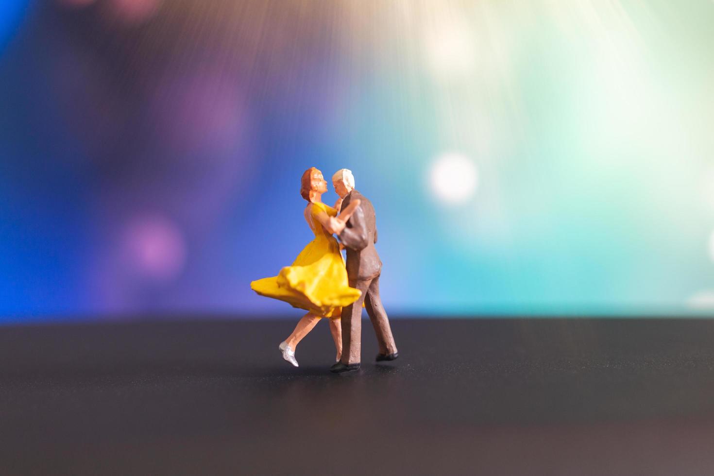 Miniaturpaar, das mit einem bunten Bokehhintergrund tanzt foto