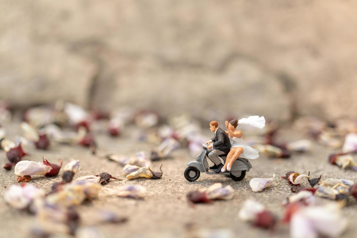 Miniaturpaar, das ein Motorrad in einem Garten fährt foto