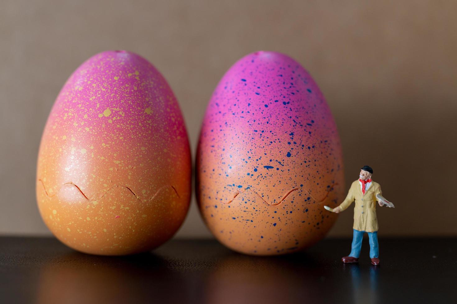 Miniaturkünstler, der einen Pinsel hält und Ostereier für Ostern malt foto