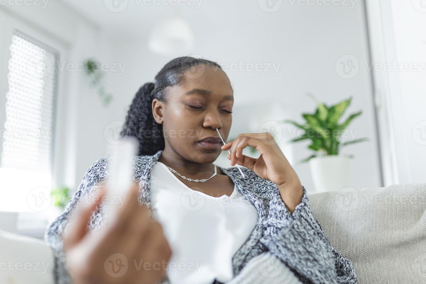 jung afrikanisch Frau halten selbst testen selbst verwaltet Tupfer und medizinisch Tube zum Coronavirus COVID-19, Vor Sein selbst geprüft beim Zuhause foto