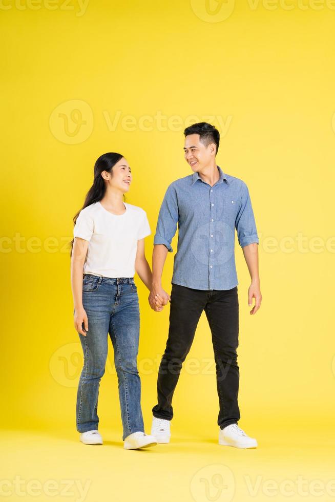 Ganzkörperbild eines asiatischen Paares, das auf gelbem Hintergrund posiert foto