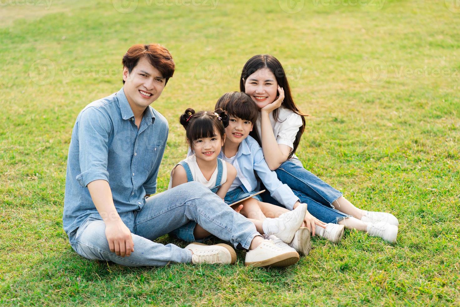 Bild von ein asiatisch Familie Sitzung zusammen auf das Gras beim das Park foto