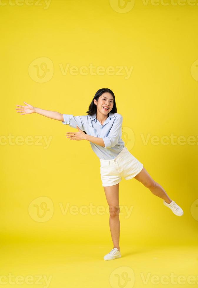 voll Körper Bild von schön asiatisch Mädchen, isoliert auf Gelb Hintergrund foto