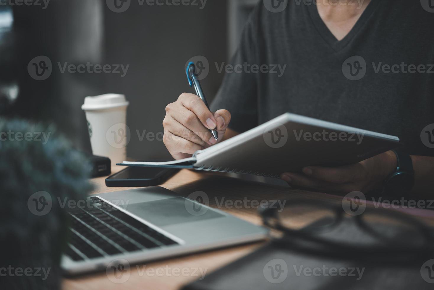 Mann Hände mit Stift Schreiben auf Notizbuch im das office.learning, Bildung und Arbeit.schreibt Ziele, Pläne, machen zu tun und Wunsch aufführen auf Schreibtisch. foto