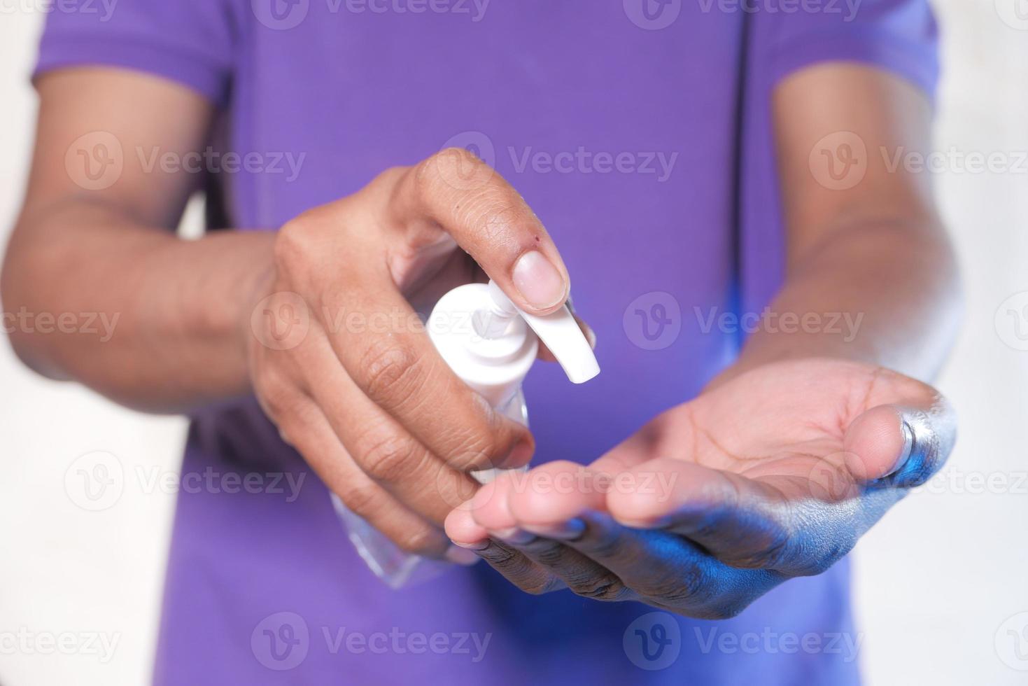 Mann im lila Hemd mit Händedesinfektionsmittel foto