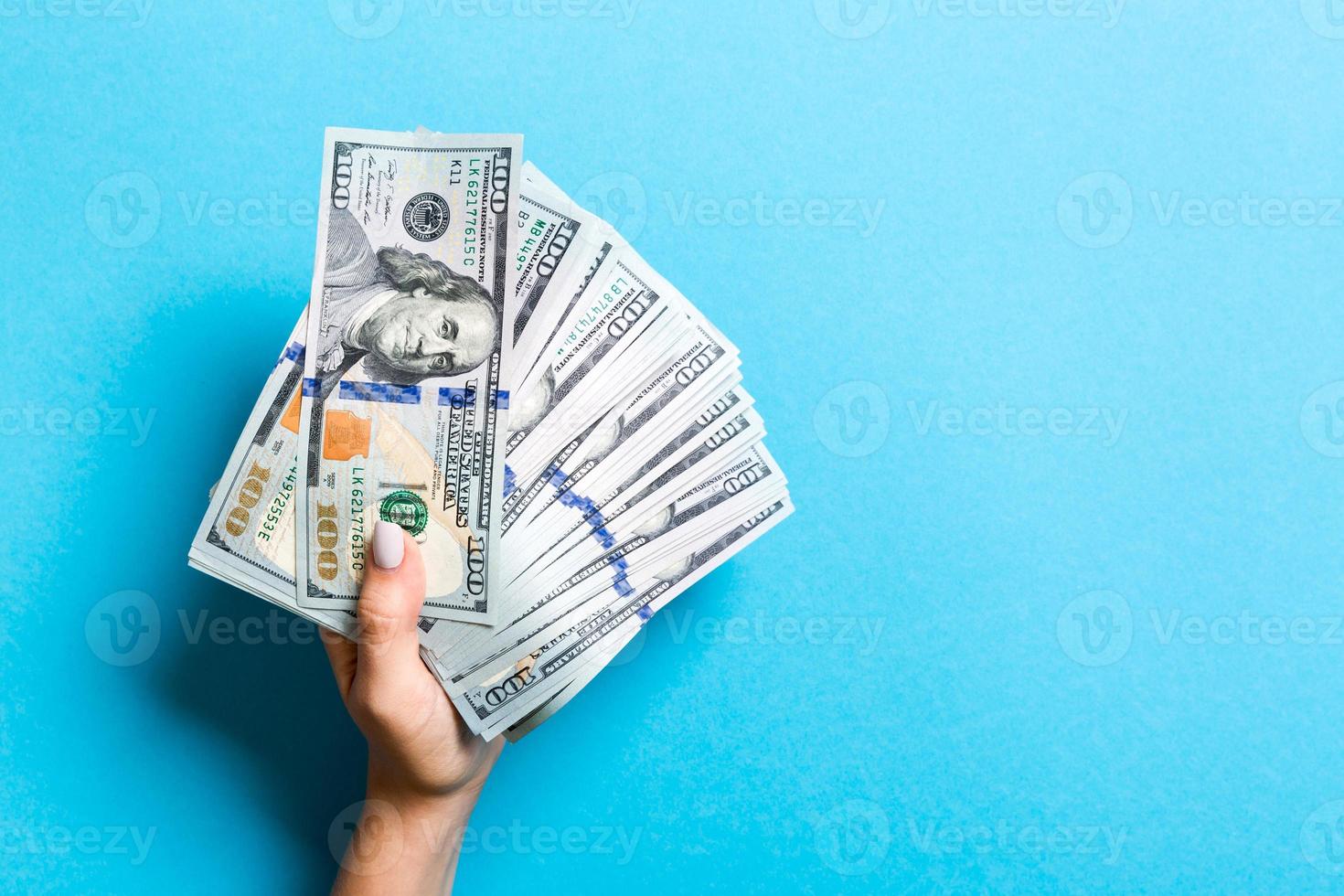 oben Aussicht von weiblich Hand halten ein Ventilator von Geld auf bunt Hintergrund. einer hundert Dollar Rechnungen. Anerkennung und Schuld Konzept mit Kopieren Raum foto