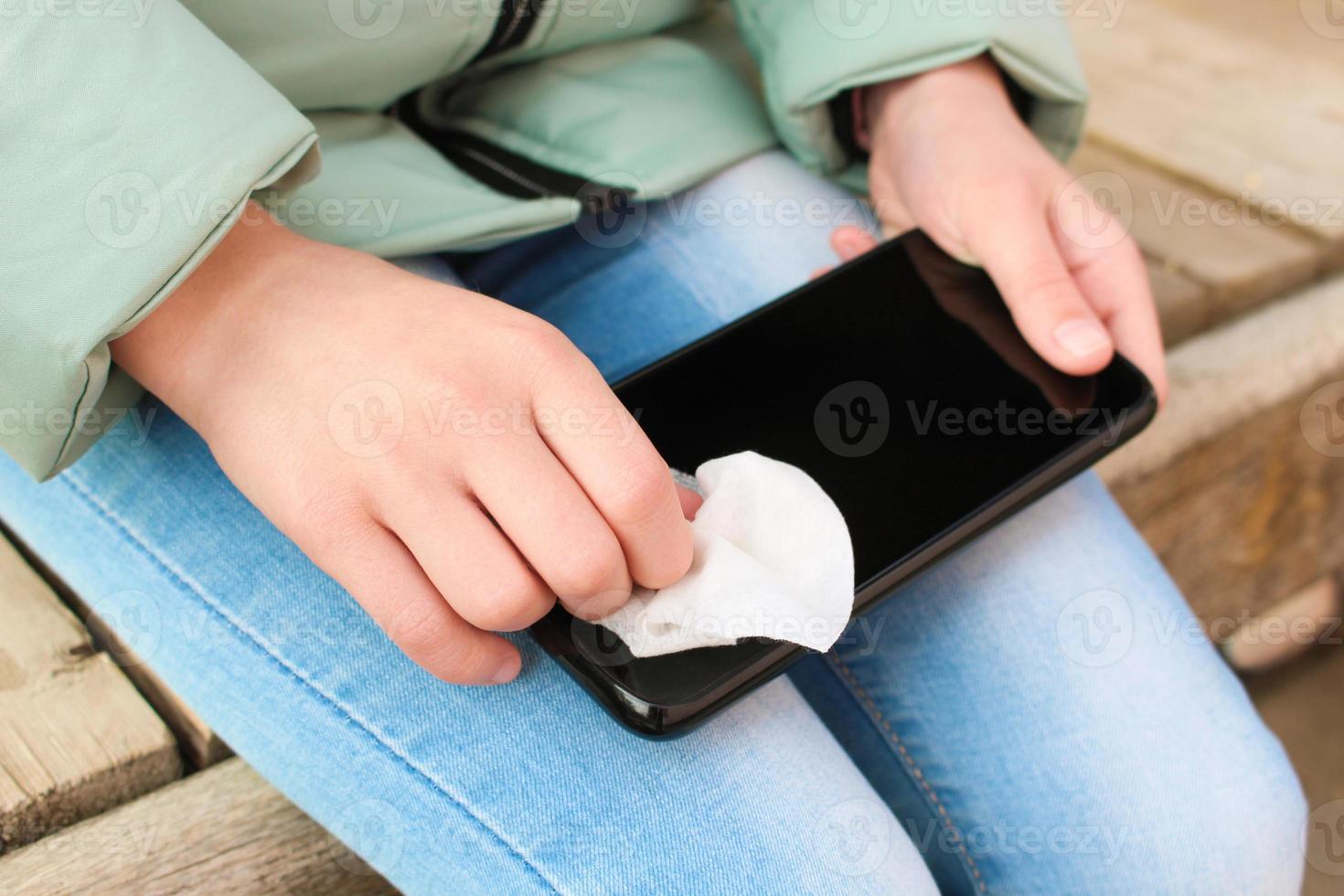 Person reinigt Handy, Mobiltelefon Telefon mit nass wischt. foto