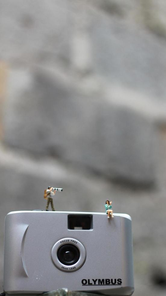 ein Miniatur Zahl nehmen Bild mit ein Kamera gegen ein echt Kamera im das Hintergrund. foto