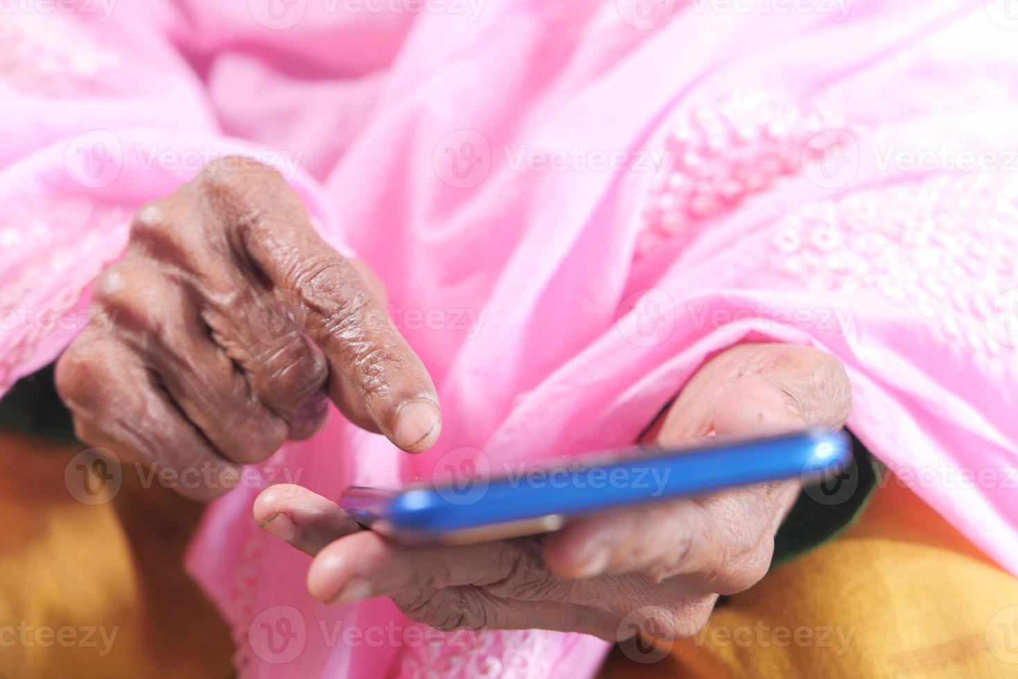 Hand der älteren Frau, die Smartphone-Nahaufnahme verwendet foto