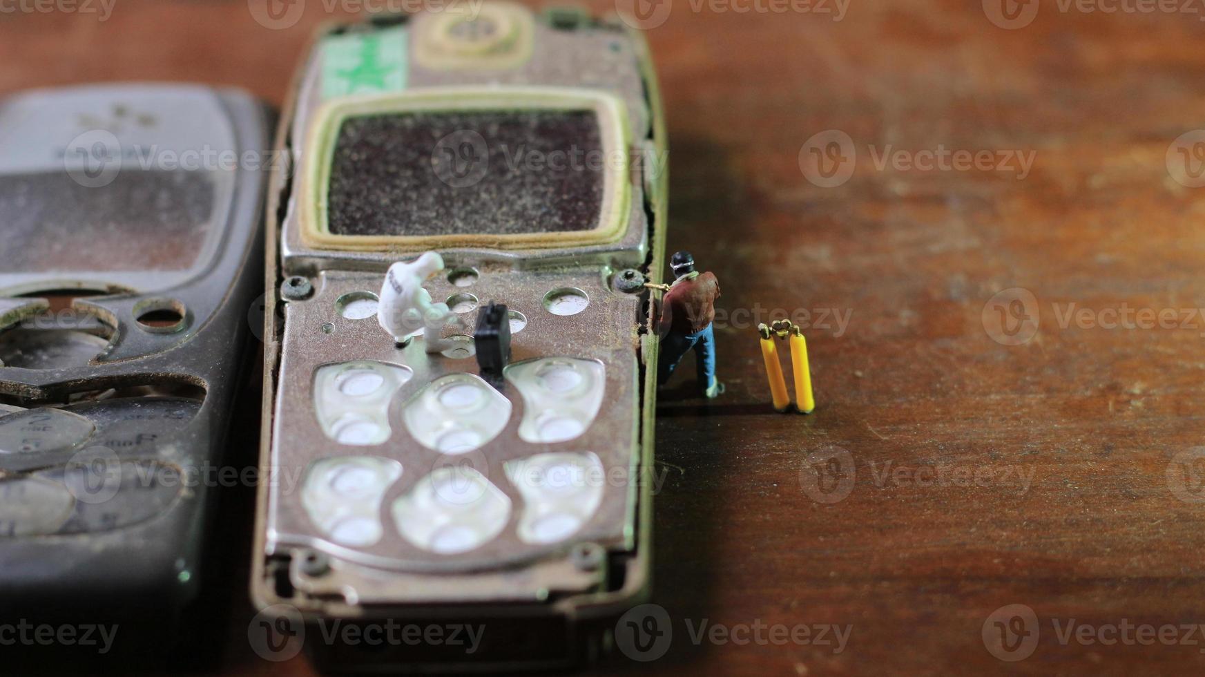 Miniatur Zahl von ein Techniker reparieren ein alt gebrochen Zelle Telefon. Arbeiten Techniker Konzept. foto