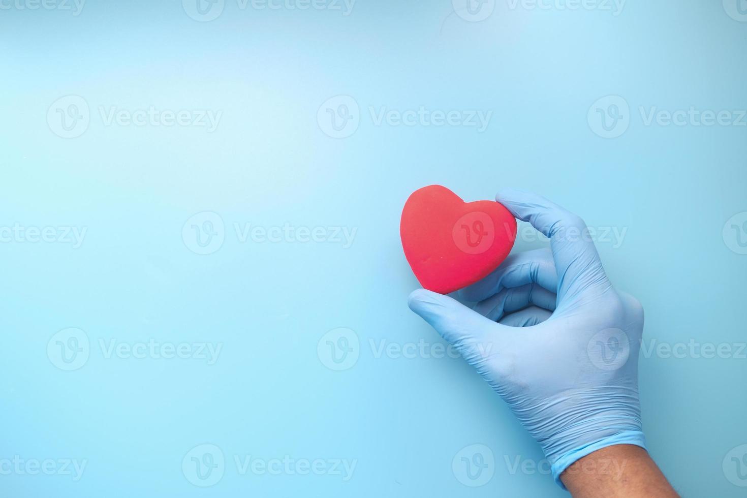 Person, die Handschuhe trägt, die rotes Herz halten foto