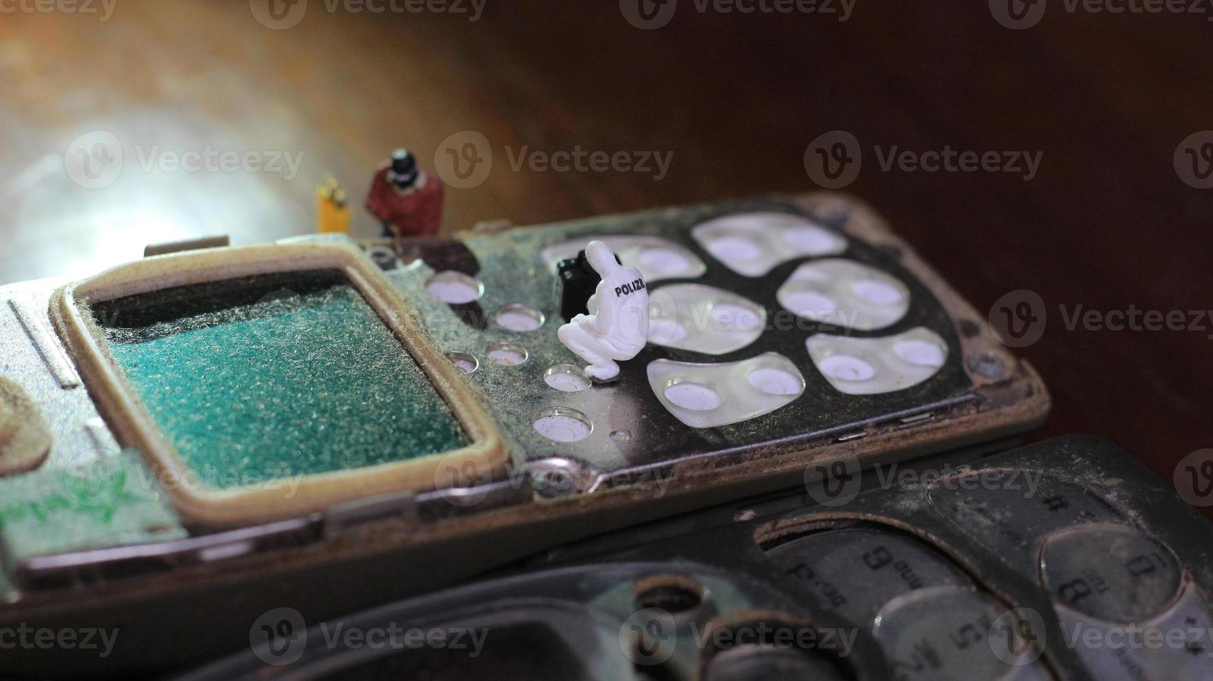 Miniatur Zahl von ein Techniker reparieren ein alt gebrochen Zelle Telefon. Arbeiten Techniker Konzept. foto