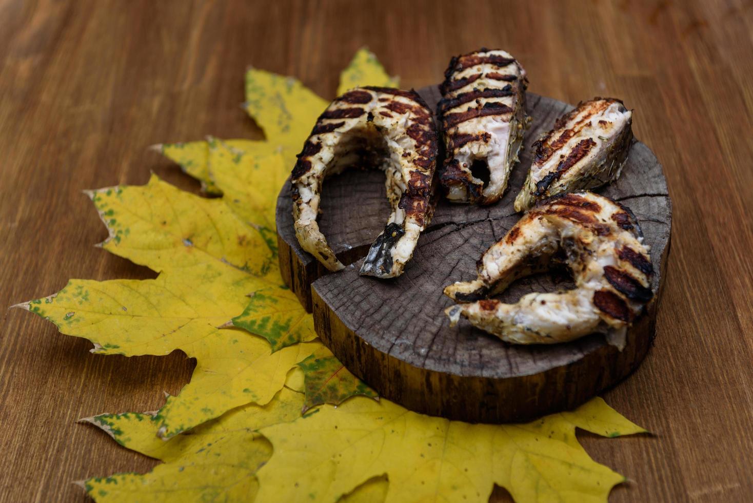 Fischsteaks gebraten auf dem Grill, der auf Baumstamm liegt foto