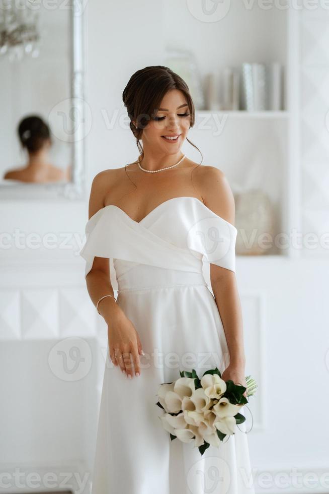 Brünette Braut im ein fest Hochzeit Kleid im ein hell Studio foto