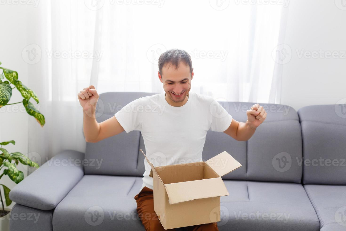 glücklich Mann mit ein öffnen Box im ein Wohnung foto