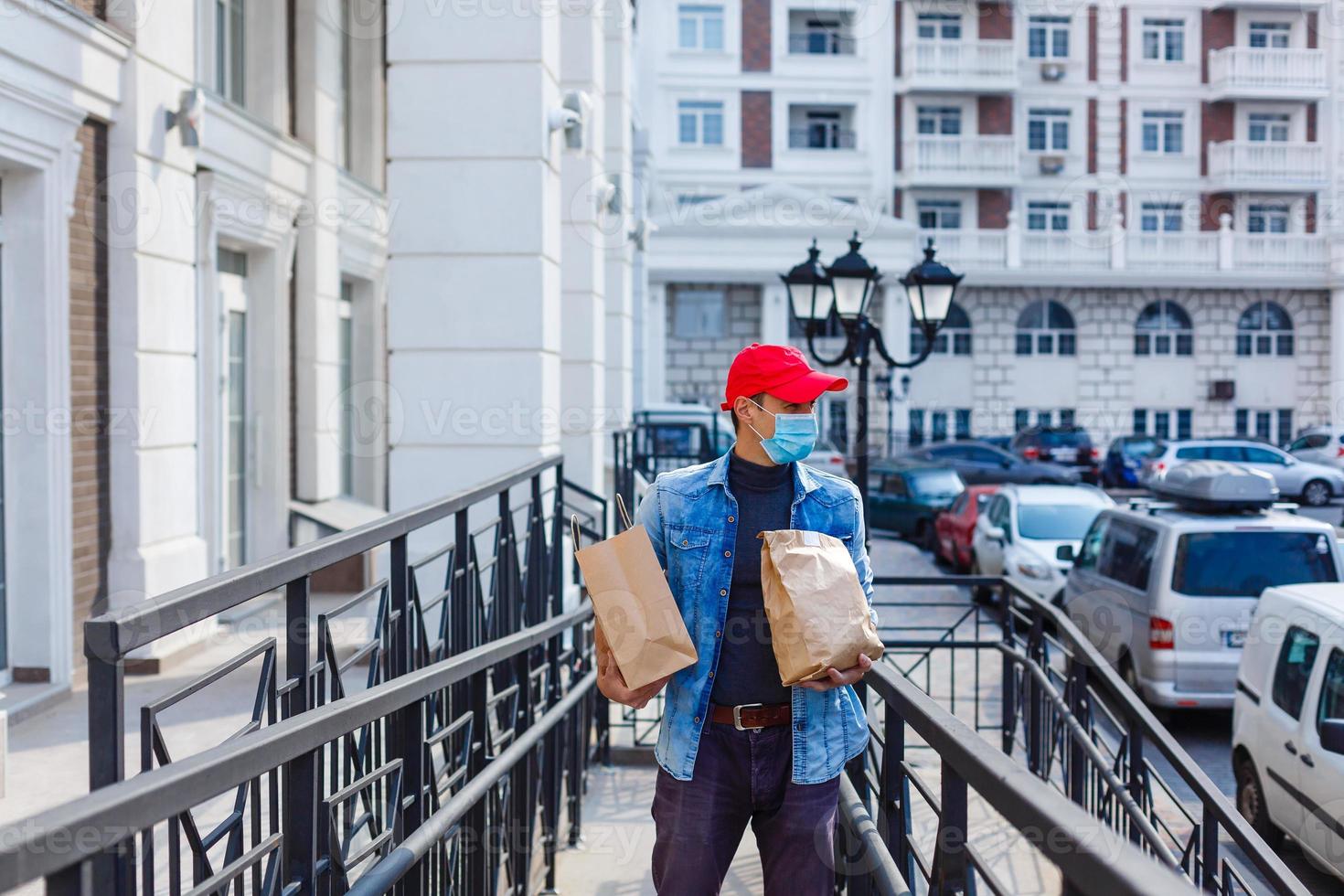 Essen Lieferung Mann mit Taschen im ein schützend Maske auf seine Gesicht foto