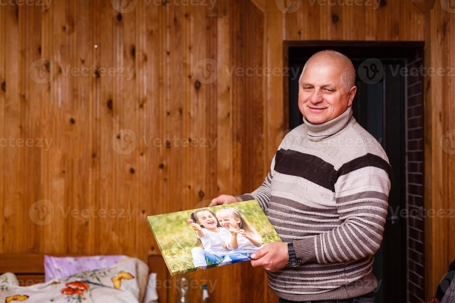 Senior Mann halten ein Foto Segeltuch von seine Enkelkinder