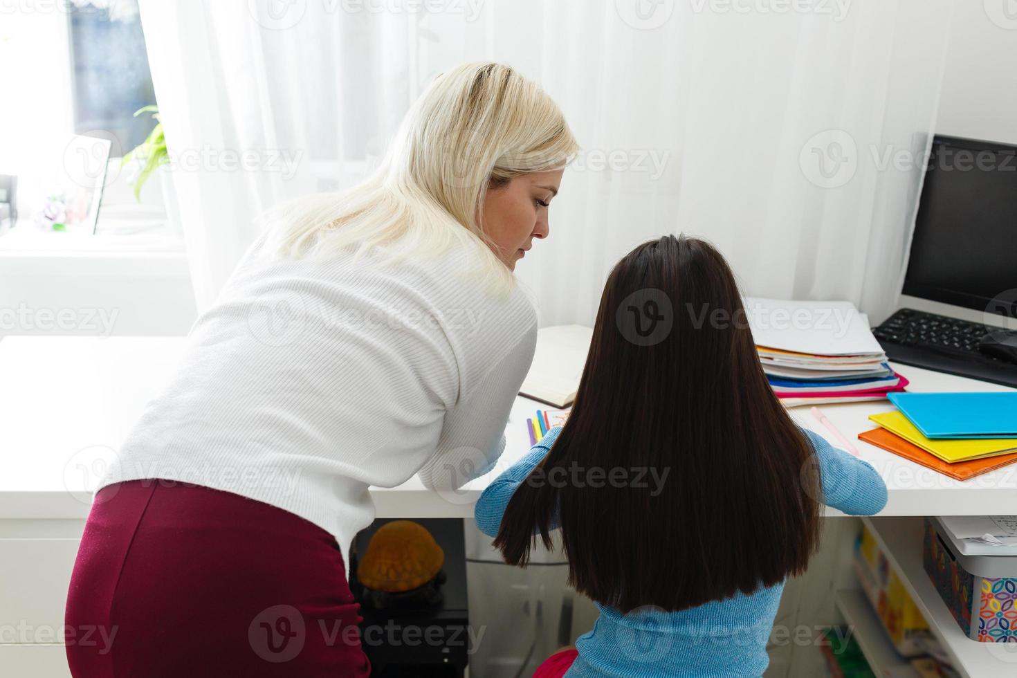 ein klein Mädchen mit ihr Mutter sind Herstellung Übungen im Heft beim Entfernung Zuhause Schulung, Quarantäne foto