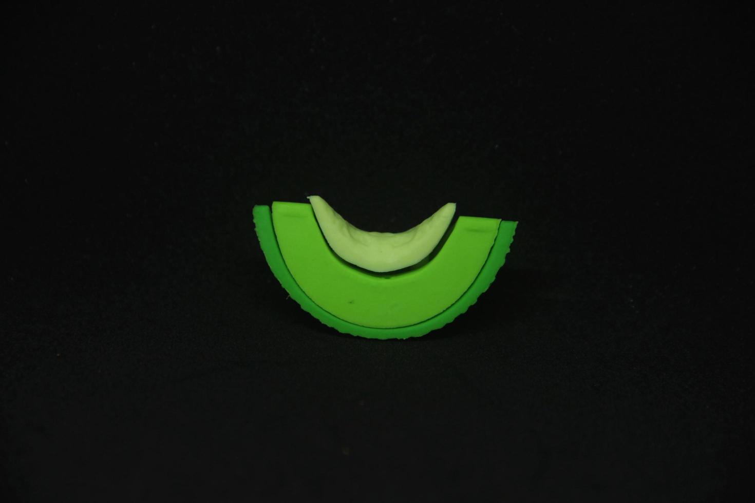 geschnitten Grün Melone geformt Radiergummi stationär Werkzeuge zum Büro oder Schule Lieferungen. isoliert Foto auf einfach dunkel schwarz Hintergrund.