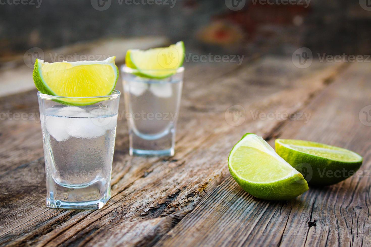 Wodka und Limette Scheiben auf hölzern Hintergrund. foto