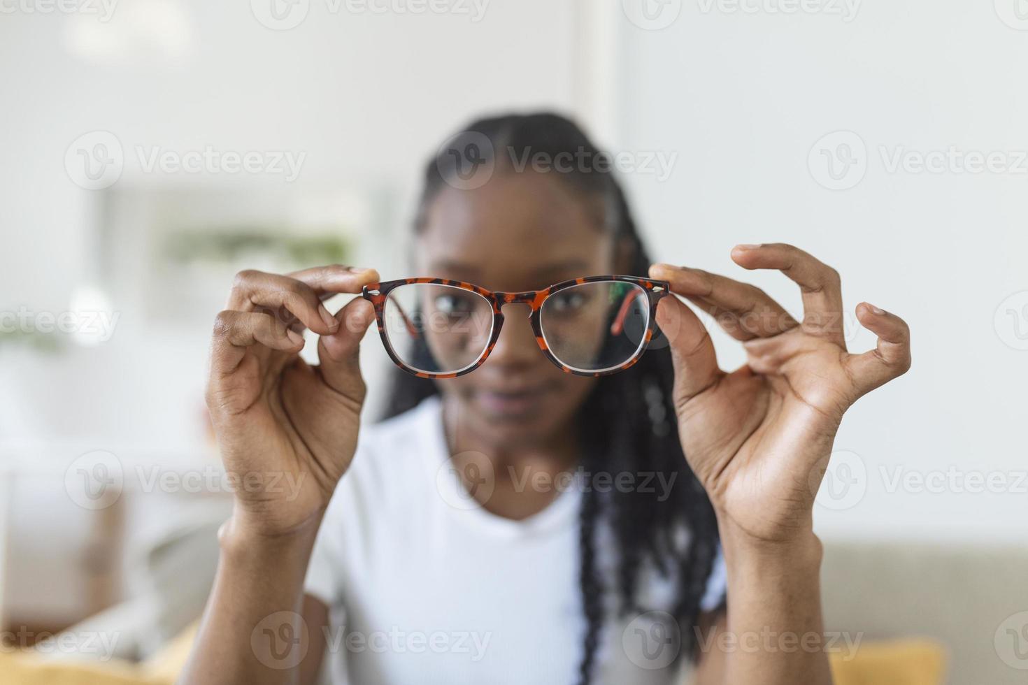 jung afrikanisch Frau hält Brille mit Dioptrie Linsen und sieht aus durch ihnen, das Problem von Kurzsichtigkeit, Vision Korrektur foto