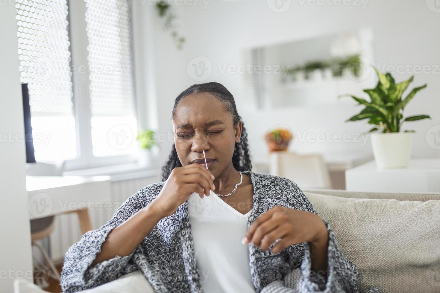 jung afrikanisch Frau halten selbst testen selbst verwaltet Tupfer und medizinisch Tube zum Coronavirus COVID-19, Vor Sein selbst geprüft beim Zuhause foto