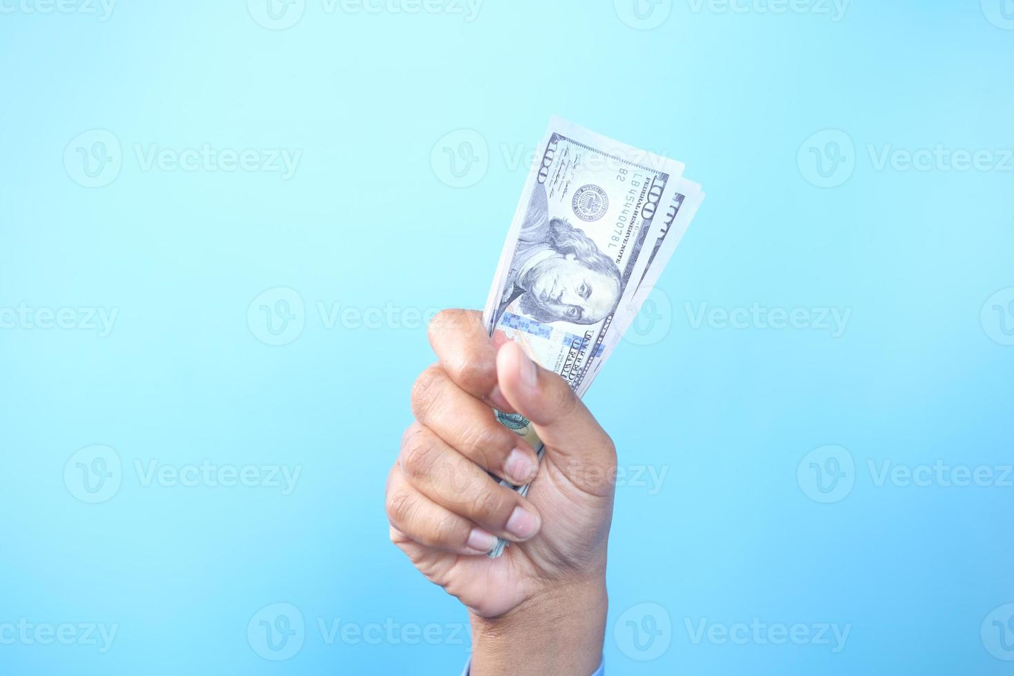Mann, der Bargeld auf blauem Hintergrund hält foto