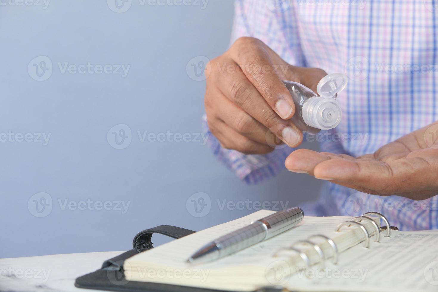 Geschäftsmann mit Desinfektionsgel auf auf Schreibtisch foto