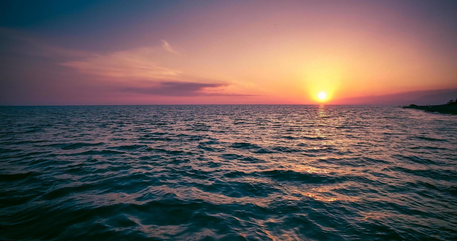 Seelandschaft mit buntem Sonnenuntergang, Bergen und Meer foto