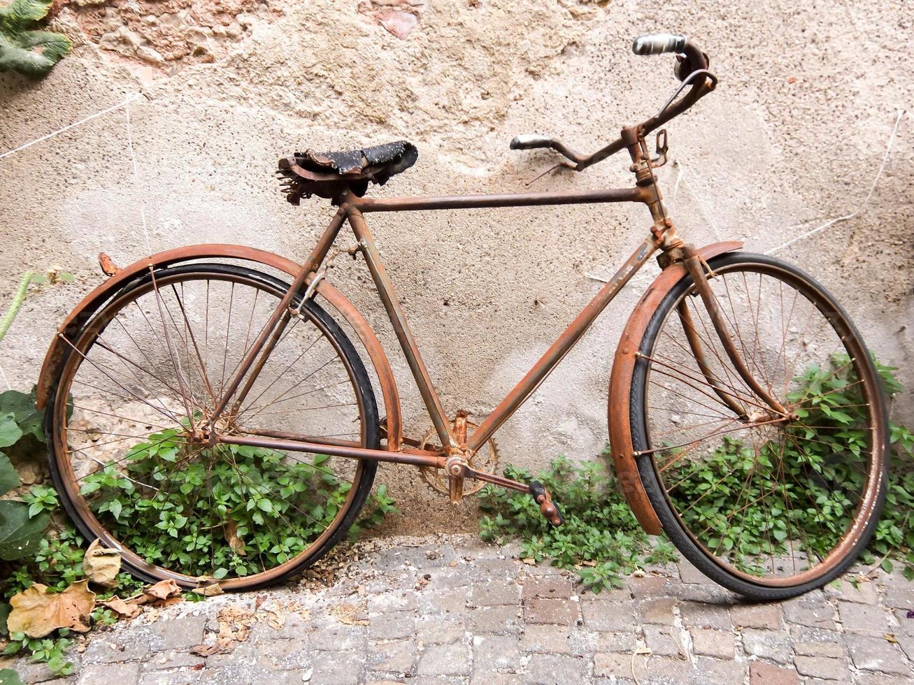 rostig alt Fahrrad durch das Mauer foto