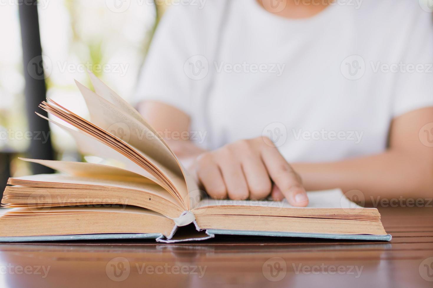 Studentin liest Buch auf dem Schreibtisch und bereitet sich auf den Test vor foto