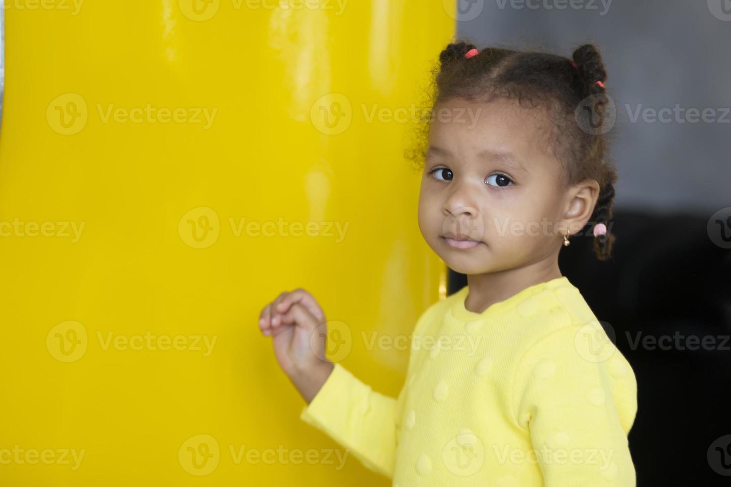 Porträt von ein wenig afrikanisch amerikanisch Mädchen auf ein Gelb Hintergrund. foto