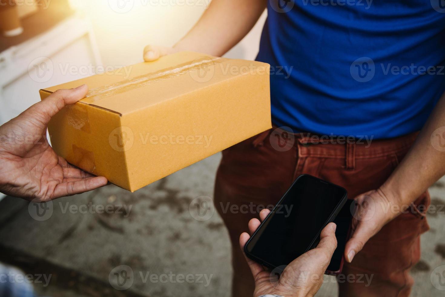 Lieferung Mann mit schützend Maske und Handschuhe liefern Pakete während Sperrung und Pandemie und halten Handy, Mobiltelefon kontaktlos Zahlung Maschine foto