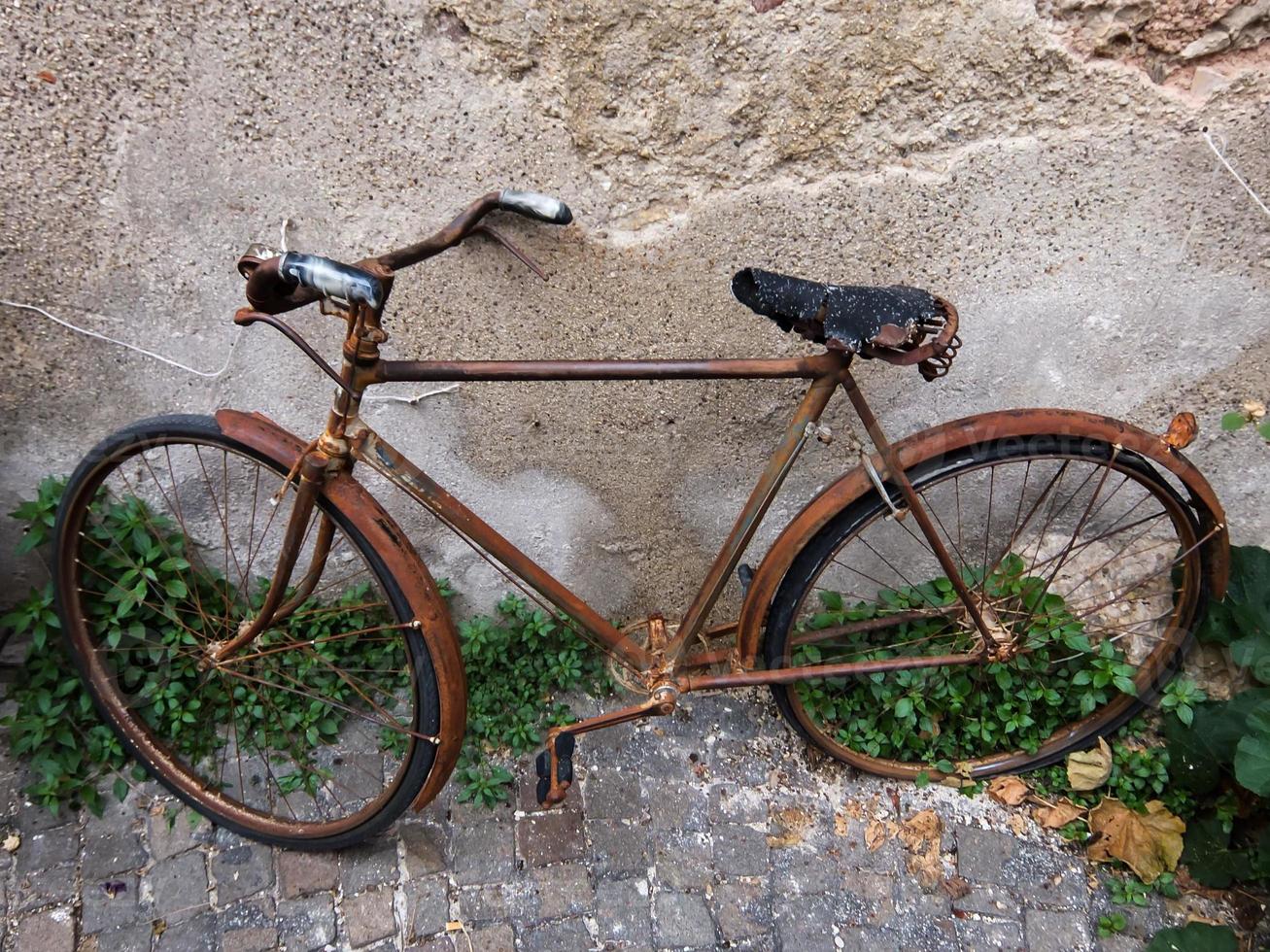 rostig alt Fahrrad durch das Mauer foto