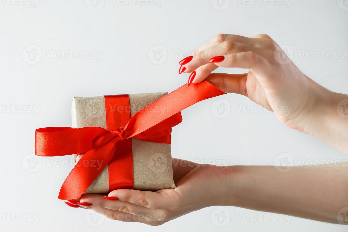 Geschenk mit einem roten Band in den Händen auf einem weißen Hintergrund foto