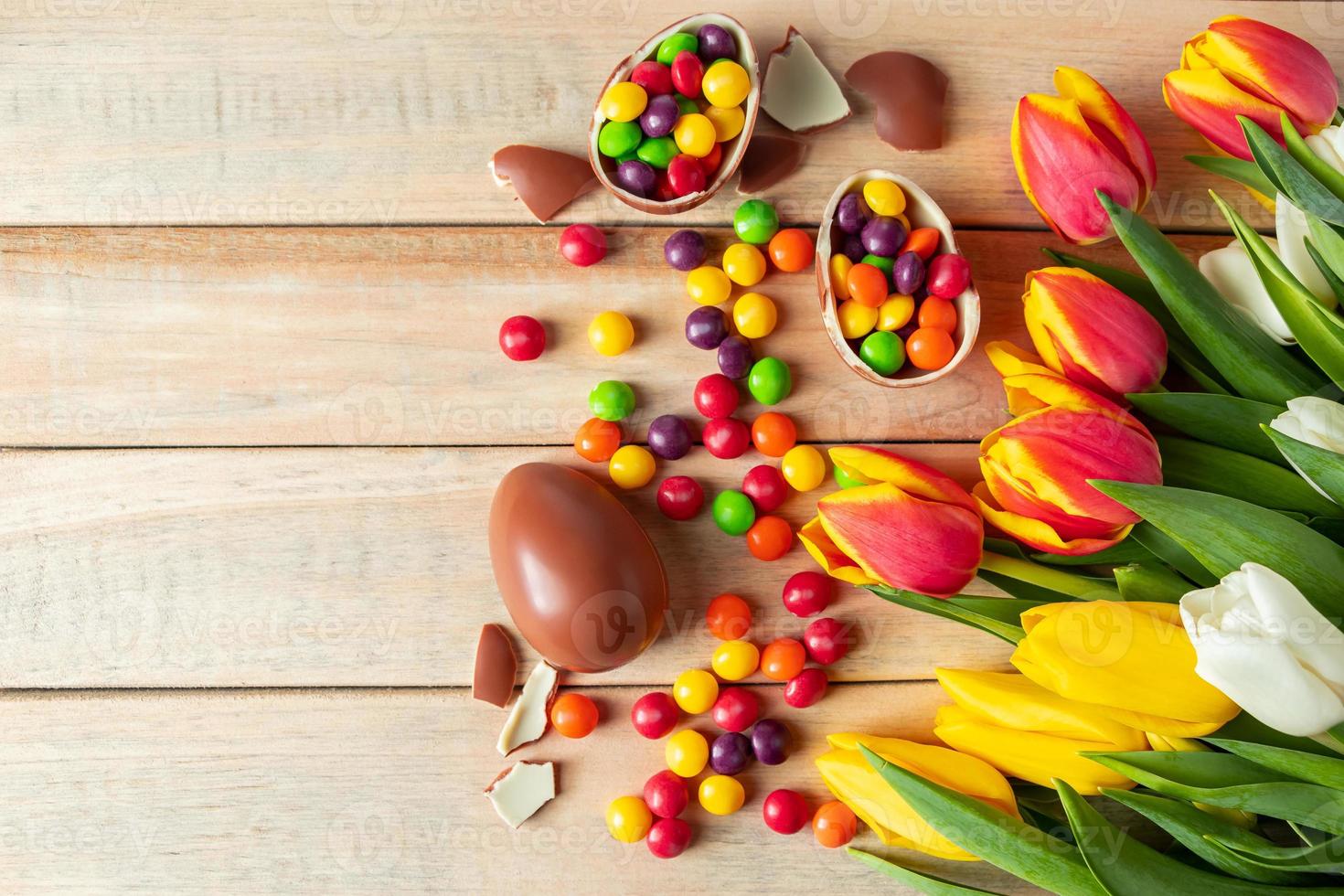 schöne rote und gelbe Tulpen für Osterferien. Schokoladeneier und Bonbons auf einem hölzernen Hintergrund. foto