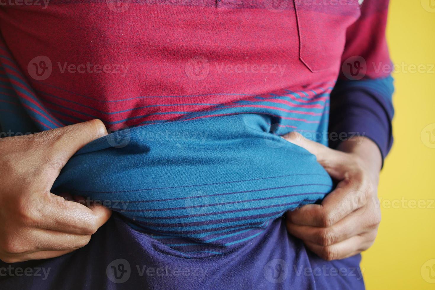 Die Hand des Mannes, die übermäßiges Bauchfett hält, übergewichtiges Konzept foto