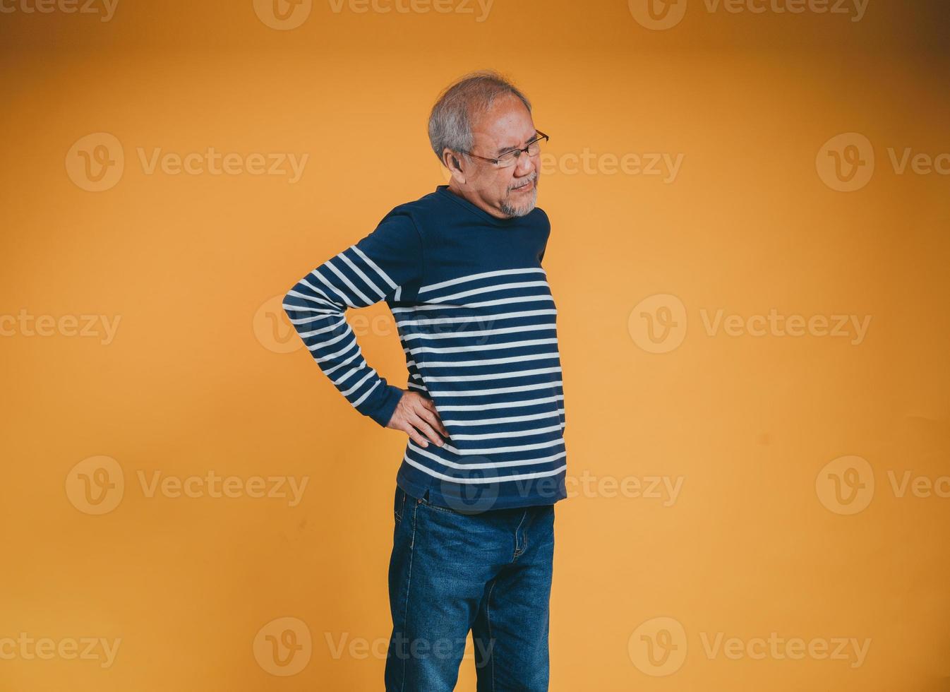 asiatisch Senior Mann Gefühl Rückenschmerzen oder zurück Schmerzen auf das Gelb Hintergrund. foto