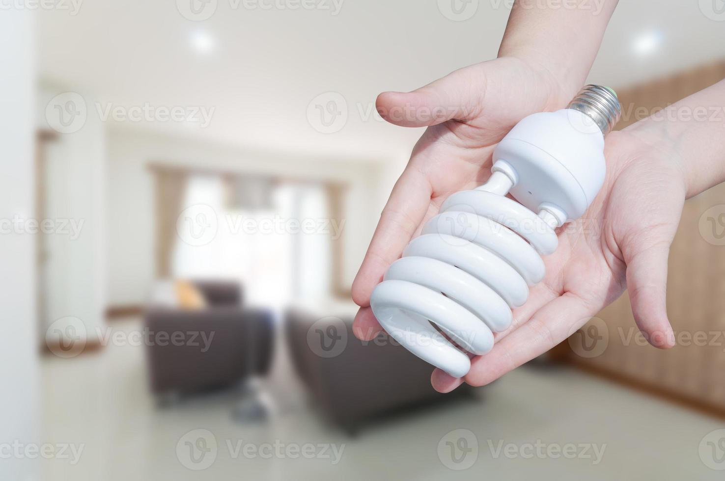 Energie Speichern Konzept, Frau Hand halten Licht Birne auf Zimmer Haus Hintergrund, Ideen Licht Birne im das Hand foto