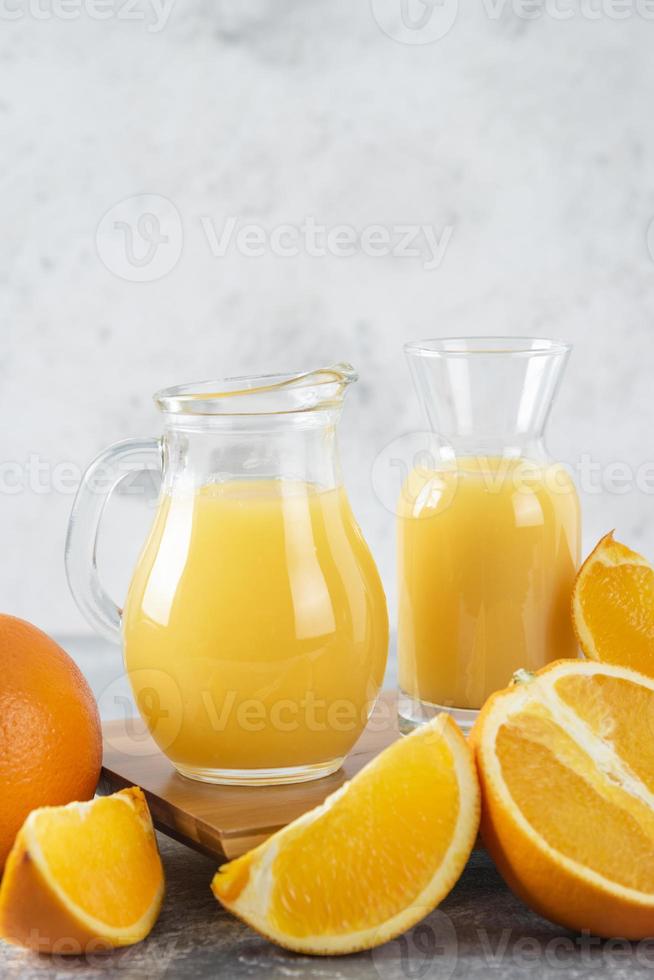 Glaskrüge mit frischem Saft mit geschnittenen Orangenfrüchten foto